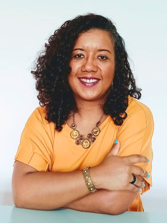 Psicóloga Liliane Nascimento sorrindo de braços cruzados